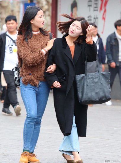 手挽手逛街的两个闺蜜，穿<em>黑色呢子大衣</em>的美女颜值高、气质好